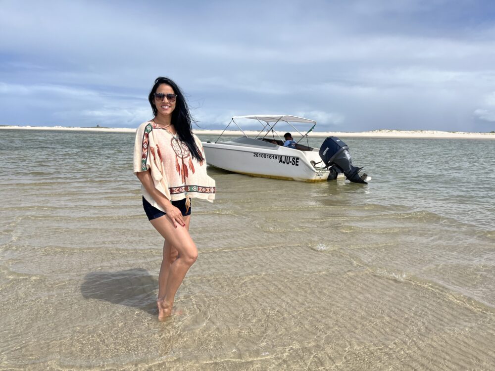 Eu no mar ao lado de uma lancha para o passeio à Ilha da Sogra, em Estância, Sergipe 