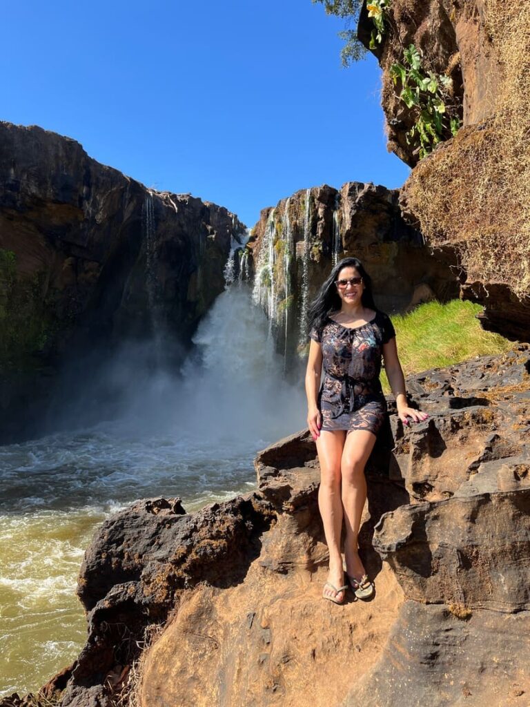 Mulher com saída de praia preta em frente a Cachoeira do Prata